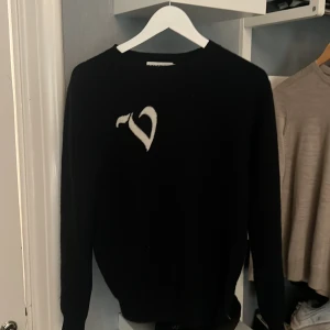 Marinblå stickad tröja från vonstudio - Svart stickad tröja från VONSTUDIO i storlek M. Tröjan har en vit V detalj på bröstet och rund halsringning. Perfekt för dig som gillar stilrena plagg med en twist. Går ej att få tag på längre 