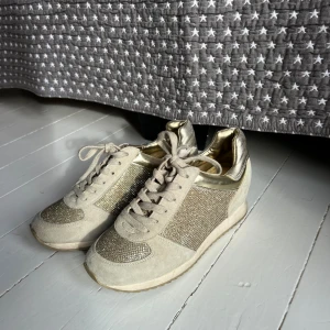 Glittriga sneakers från Nine West - Sneakers i beige och guld från Nine West💕 Kul om man vill ha en fin detalj till outfiten eller perfekt för temafester! Aldrig använda!