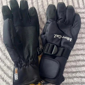 Svarta snowboardhandskar Vert-Cal - Svarta snowboardhandskar från Vert-Caz med MaxDry-system för extra andningsförmåga. Handskarna har justerbart spänne vid handleden, förstärkta fingertoppar och breda muddar. Perfekta för vinterns äventyr i backen.