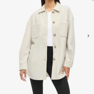 Skjortjacka - Skjortjacka i beige med stora bröstfickor och knappar framtill. Jackan har klassisk krage, lång ärm och en loose passform. Aldrig använd men tvättad därav inte helt som ny men väldigt fint skick! Pris går absolut att diskutera! Nypris 499 kr