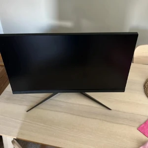 Gaming Monitor msi 27tum 180hz - Stilren och modern gaming-skärm med tunn ram och stabilt stativ. Skärmen ser ut att vara i mycket gott skick utan synliga repor eller skador. Perfekt för spel eller arbete med bred bildyta och elegant design.