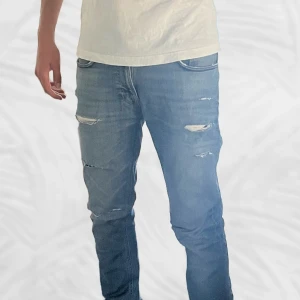 Blå Nudie Jeans med slitningar  | Slim fit  - Säljer ett par blåa slim jeans från Nudie med slitningar. Slitningarna är customized. Går att ta bort de som man inte vill ha dem helt gratis i en nudie butik. Jeansen är riktigt sköna - tillverkade i fin bomull. Perfekt för en stilig look. Tveka inte på att höra av dig vid minsta tanke eller fundering! 😁