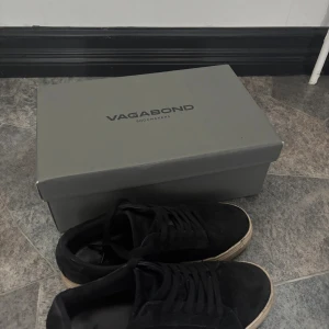 Svarta sneakers från Vagabond i mocka - Svarta sneakers från Vagabond med ovandel i mjuk mocka och klassisk snörning. Skorna har en vit, något smutsad platt sula och rund tå. Perfekta för en stilren och avslappnad look. Nypris 1400kr mitt pris 730