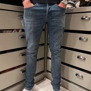 Blå dondup George - Snygga blå dondup George jeans med skinny passform. Jeansen har en lätt tvättad look, normal midja och smala ben. Tillverkade i stretchig denim för extra komfort. Perfekta för dig som gillar en modern och slimmad stil.                  Skick=helt nya med tags nypris=3000