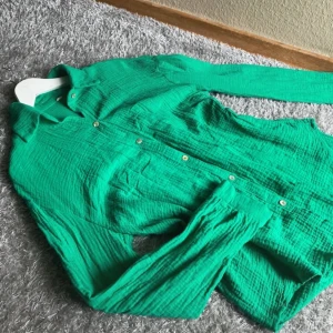 Grön skjorta i bomull med knappar - Snygg grön skjorta i mjukt och luftigt bomullstyg med krage och långa ärmar. Skjortan har en klassisk passform och knäpps med små, runda knappar framtill. Perfekt för dig som gillar färg och vill ha en chill och bekväm stil.