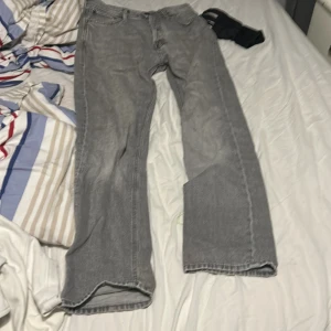 Gråa relaxed jeans från Jack & Jones - Säljer ett par gråa jeans från Jack & Jones, modell Relaxed/Chris. De har en avslappnad passform med raka ben och klassisk femficksdesign. Jeansen är tillverkade i bomull och har en snygg, ljusgrå tvätt som ger en cool vibe.