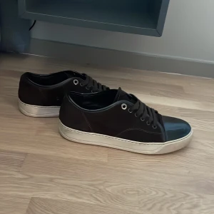 Bruna sneakers med vit sula - Bruna lanvins med vit platt sula. Ovandelen är i mocka och tån är i blankt brun material som ger en cool kontrast. Låg modell med rund tå och metallfärgade öljetter. Perfekt för dig som gillar stilrena och enkla skor. Tar emot byten, helst valentino open 
