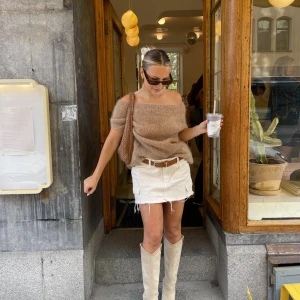 Beige offshoulder stickad topp - Superfin beige stickad topp från design by si, med offshoulder-modell. Toppen är fluffig och mjuk, har en bred halsringning som sitter snyggt över axlarna. Storlek XS/S. Perfekt att styla med både jeans och kjol! Använd 3 gånger så skicket är väldigt fint. Skriv vid frågor!