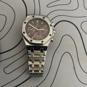 Monteya silverfärgad klocka - Stilren klocka från Monteya i silverfärgat rostfritt stål. Klock bandet är samanlagt 21 cm långt vad jag kunde mästa iallafall utan själva klockan.