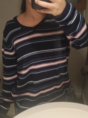 Randig mörkblå stickad tröja - Mysig stickad tröja i mörkblått med ränder i vitt, rosa och ljusblått. 100% cotton. Anledningen till att jag säljer den är för att jag rensar min garderob. Står ingen storlek men jag har S/M och jag är 155cm, Jag accepterar mindre bud.