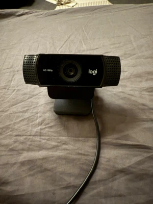 Logitech HD 1080p Webcam - Snygg Logitech HD 1080p webbkamera med bred montering och USB-anslutning. Perfekt för videomöten och streaming. Kameran ser ut att vara i gott skick utan synliga repor eller skador. Enkel att fästa på skärm eller laptop.
