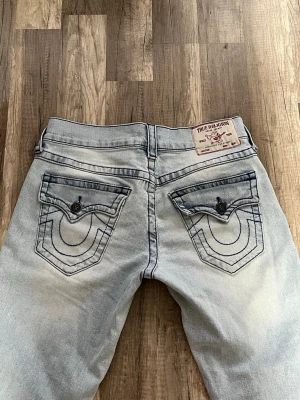 True religion Billy jeans  - Säljer dessa supersnygga jeans som är använda 1 gång. De har mörkblå sömmar! Köpta för ca 2000kr i Stockholm! Storlek 28, passar en S/M beroende på hur man vill att de ska sitta. Unisex så passar både tjejer o killar. Midjemått rakt över: 40cm innerbens längden: 81cm,  från hela midjan upp ifrån och ner till slutet av benet: 105cm. Brukar ha 36 i jeans för referens. 