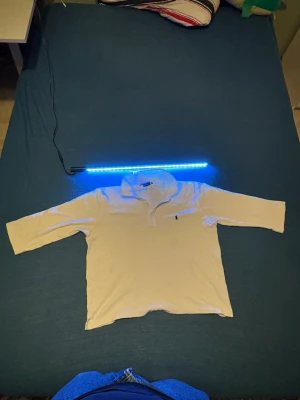 Vit långärmad polotopp Ralph Lauren - Klassisk vit långärmad polotopp från Ralph Lauren Sport med krage och knappar framtill. Toppen har den ikoniska broderade loggan på bröstet och är gjord i ett mjukt bomullsmaterial. Perfekt till jeans eller kjol för en clean och tidlös look. Finns någon fläck men går att tvättas