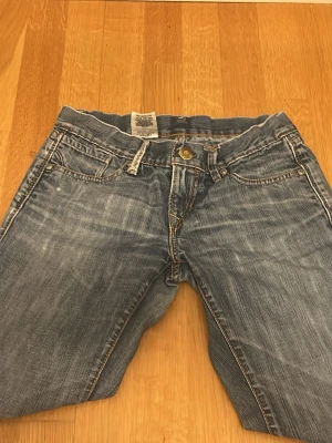 Levis 501 ljusblå jeans - Klassiska Levis 501 jeans i ljusblå tvätt med slitningar och distressed detaljer på bakfickan. Flare passform och femficksmodell med knappgylf. Tillverkade i tålig denim av bomull. Perfekta för en avslappnad och trendig look. Skriv gärna om det behövs bättre bilder mått osv❤️