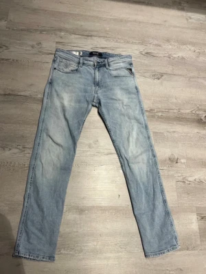 Replay anbass jeans - Säljer ett par ljusblå jeans från Replay i rak modell. Jeansen har klassisk femficksdesign, normal midja och är tillverkade i ekologisk bomull. Snygg tvätt med subtila slitningar och Replay-logga på bakfickan.