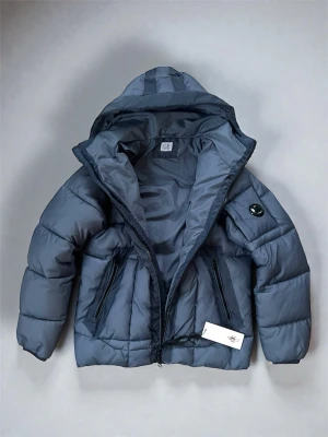 Blå dunjacka från C.P. Company - Oanvänd CP Company jacka i L från julklapp, lite tight på mig och säljer därav (195, 90kg). Helt ny med etikett, huva och logopatch. Nypris ~7000 kr, mitt pris: 1490 – totalt fynd! Skickar samma dag som köp. Hör av er för funderingar🫡