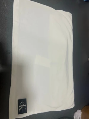 Vit t-shirt från Calvin Klein Jeans - Clean vit t-shirt från Calvin Klein Jeans med klassisk rund hals och korta ärmar. Tillverkad i mjuk bomull och har en svart CK-logga nertill på framsidan. Enkel och stilren modell som passar till allt. Använd en gång. 