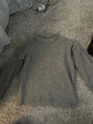 Grå stickad tröja från 157 XS/S - Mysig grå stickad tröja från 157 i storlek XS/S. Tröjan har en klassisk rund halsringning, ribbade muddar och är långärmad. Perfekt för lager på lager under kyliga dagar och enkel att matcha med allt.
