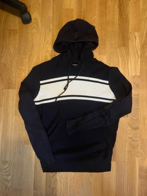 Stickad hoodie från sprinfield - Säljer denna fina stickade hoodie från Springfield, hoodie har en cool design med vita streck. Skriv vid frågor!