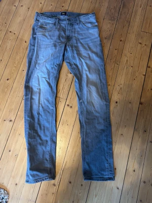 Grå Lee Daren Zip Fly jeans W31 L34 - Säljer ett par grå jeans från Lee, modell Daren Zip Fly. Klassisk femficksdesign, raka ben och normal passform. Jeansen har dragkedjegylf och Lee-logga på bakfickan. Perfekta till en avslappnad stil och tillverkade i mjuk bomull. Skick 8/10 behövs strykas men använda sparsamt 