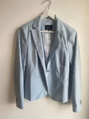 Ljusblå kavaj från STOCKH LM, strl 38 - Snygg ljusblå kavaj från STOCKH LM i storlek 38. Klassisk modell med slag, knäppning fram och fickdetaljer. Tillverkad i en mix av bomull och polyester med mjukt foder. Perfekt för dig som vill ha en stilren och fräsch look. Byxa finns till i stl 40 i separat annons. 