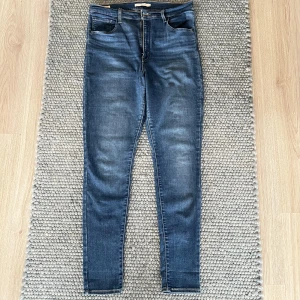 Levi's jeans, Mile high super skinny - Säljer ett par klassiska Levi's skinny jeans i mörkblå tvätt. Modell Mile high super skinny. De har fem fickor, dragkedja och knapp framtill samt den ikoniska röda Levi's-lappen på bakfickan. Jeansen är tighta hela vägen ner och har hög midja. 