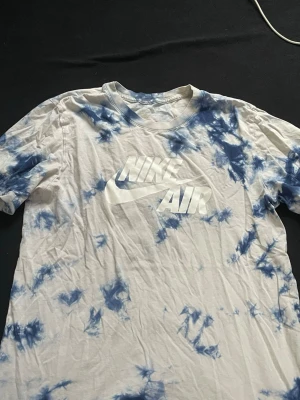 Nike Air tie-dye t-shirt blåvit - Säljer en snygg Nike Air t-shirt med blåvit tie-dye mönster och stor logga framtill. T-shirten har korta ärmar och är gjord i mjuk bomull, perfekt för en chill och sportig look.