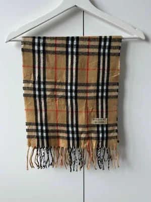 Burberry halsduk - Klassisk Burberry scarf i beiget rutmönster med fransar. Enkel att matcha och perfekt för kyligare dagar. | 100 % kashmir | Mått: ca 168 × 30 cm | Mycket bra skick | Hör gärna av dig vid frågor eller funderingar 😄|
