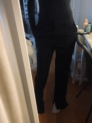 Svarta kostymbyxor med slits - Säljer ett par svarta kostymbyxor från NA-KD i storlek 32. Prislapp kvar.