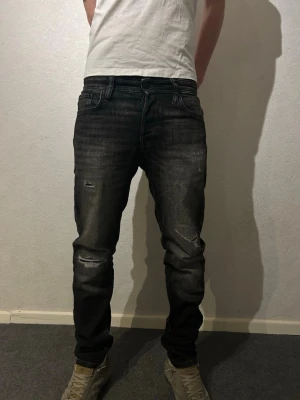 jeans Jack & Jones -  jeans från Jack & Jones, modell Tapered/Mike. Jeansen har en tvättad look med slitningar på knäna. Skick 10/10 förutom ett liten slitning som blivit typ see trough som jag har lagat och inte märks av 