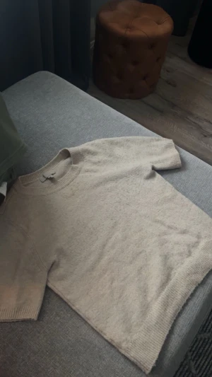 Beige stickad tröja från H&M - En enkel och snygg beige stickad tröja från H&M i storlek XS. Tröjan har korta ärmar, rund hals och ribbade muddar vid hals, ärmslut och nederkant. Vid snabb affär kan jag gå ner i pris! Skriv även om man vill ha flera bilder, till exempel om man vill se hur den ser ut på!🥰