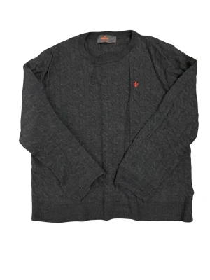 Mörkgrå stickad tröja från Morris - Snygg mörkgrå stickad tröja från Morris med diskret kabelstickat mönster och röd broderad logga på bröstet. Tröjan har rund hals och långa ärmar med ribbade muddar. Perfekt för dig som gillar klassisk stil med en twist. (BVSA!!!)