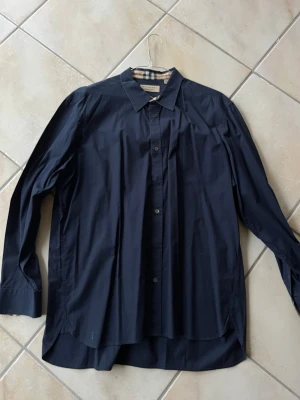 Mörkblå Burberry skjorta XXL - En snygg klassisk mörkblå Burberry skjorta i ett mycket bra skick. Skjortan passar perfekt för sommarkvällar, utekvällar eller för vardagligt bruk. Pris är inte hugget i sten, hör av dig vid funderingar och frågor🤗✌🏼
