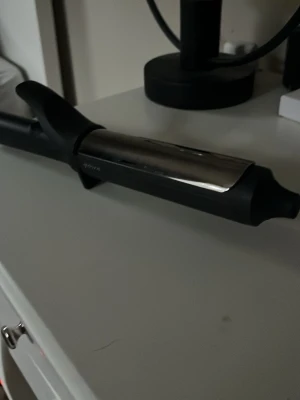 Svart och silver locktång från Philips - Snygg locktång från ghd. Perfekt för att fixa mjuka lockar och waves. Stilren design som passar på sminkbordet och är enkel att använda för både nybörjare och proffs. Materialet är mindre slitsamt på håret.