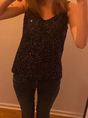 Marinblått glittrigt linne  - Säljer ett marinblått glitterlinne i superskick! Perfekt till till exempel nyår och annan fest! Linnet är v-ringat och mjukt tyg på insidan, så det är superbekvämt även fast det är en paljettröja. Använd varsamt endast två gånger 🥰