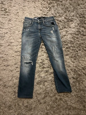 Ljusblåa Replay jeans med slitningar. - Säljer ett par blåa jeans från Replay med coola slitningar och hål på benen. W29 L32