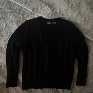 En svart stickad ralph lauren tröja - Köpte denna i sommras då den fortfarande är i bra skick.