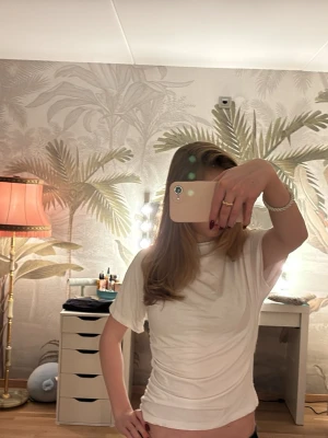 Vit t-shirt med rynkade sidor - Säljer en vit t-shirt med korta ärmar och rund hals. T-shirten har snygga rynkade detaljer längs sidorna som ger en cool och figurnära passform. Materialet känns mjukt och lätt.