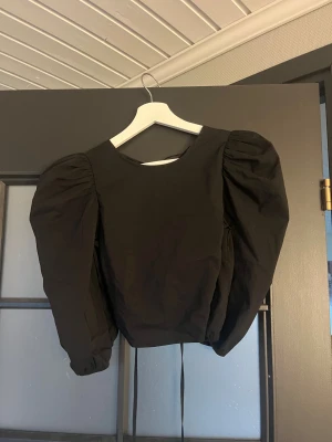 Svart blus med puffärmar Gina Tricot - Säljer en svart blus från Gina Tricot i storlek 34. Blusen har långa puffärmar, croppad passform och snygg snörning i ryggen. Perfekt för dig som gillar trendiga detaljer och vill sticka ut lite extra.