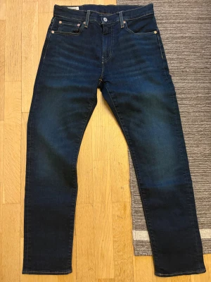Levi's 502 mörkblå jeans W30 L30 - Mörkblå Levi's 502 jeans med klassisk femficksdesign och snygga kontrastsömmar. Jeansen har rak passform och är tillverkade i slitstarkt denimtyg. Perfekta för dig som gillar en tidlös och stilren look.