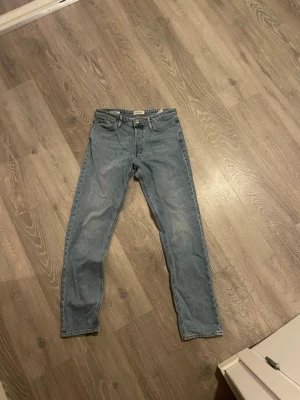 Jack and Jones ljusblå relaxed jeans 30/34 - Ljusblå Jack and Jones jeans i relaxed passform, klassisk femficksmodell med raka ben och normal midja. Jeansen är tillverkade i slitstark bomull och har en tidlös look med Jack and Jones patch bak i midjan. Perfekt för dig som gillar avslappnad stil.