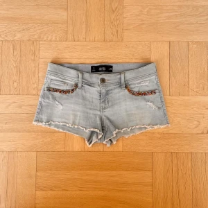 Ljusblå jeansshorts med pärldetaljer - Snygga ljusblå jeansshorts från Hollister med slitna detaljer och råa kanter, mått syns i annonsen🫶🫶