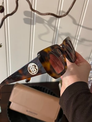 Bruna Burberry solglasögon  - Säljer mina fina solglasögon från Burberry då jag inte använder de längre.  Modellen Daisy, mått: 51mm, i färgen havana. Har alla tillbehören, inkl boxen. Inga defekter, inga synliga skador. Bra varsamt bruksskick. Kostar ca 3400kr på Synpotik 🥰