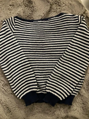 Mörkblå randig one-shoulder tröja - En jättegullig one-shoulder tröja. Den är stickad i randig vit och mörkblå (lite ljusare i verkligheten än på bilden). Aldrig använd! Köpte nyss.