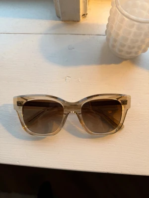 Beige transparenta solglasögon - Snygga solglasögon med transparent beige båge och bruna tonade glas. Rektangulär form som ger en modern och trendig look. Perfekta för att lyfta din stil under soliga dagar.