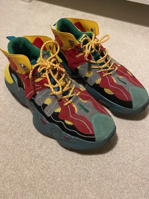 Färgglada sneakers med retrovibe - Unika sneakers i flera färger med vågiga detaljer i rött, gult, grönt och grått. Skorna har tjock sula, snörning och mix av mocka och syntetmaterial. Perfekta för dig som vill sticka ut med din stil. Stl 44, priset är förhandlingsbart