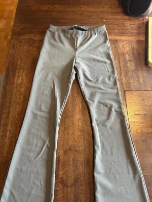 Grå bootcut leggings - Snygga grå leggings från 157 med bootcut-modell. De har en enkel och clean design utan synliga detaljer och är tillverkade i ett stretchigt material som sitter skönt på kroppen. Perfekta för dig som gillar en stilren look med lite vidare ben.