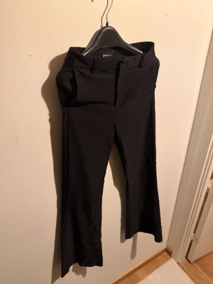 3 st kostymbyxor gina tricot  - Säljer ett par svarta bootcut byxor från Gina Tricot i storlek 38. Byxorna har en klassisk passform med utsvängda ben och stängs med knapp och dragkedja. Perfekta till en snygg topp eller hoodie.