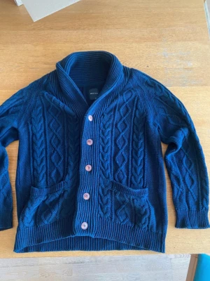 Kabel stickad kofta - Skitsnygg kabel stickad kofta, den är både tjock och varm runt nacken men även väldigt andningbar. I väldigt fint skick! Från ett japanskt märke i hög kvalitet! Vid ytterligare frågor är de bara att fråga☺️