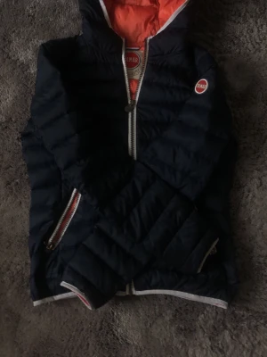 Mörkblå pufferjacka från Colmar - Säljer en mörkblå pufferjacka från Colmar med silvriga dragkedjor framtill och på fickorna. Jackan har en kortare passform och quiltad design. Perfekt för kyligare dagar och enkel att matcha med olika outfits. En måste i garderoben!